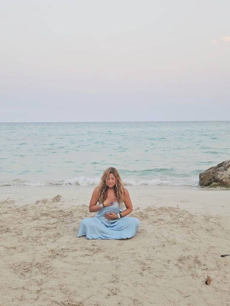 Dina Al Hidiq Zebib meditating by the sea on the beach in mallorca guided breathing and meditation at sunset