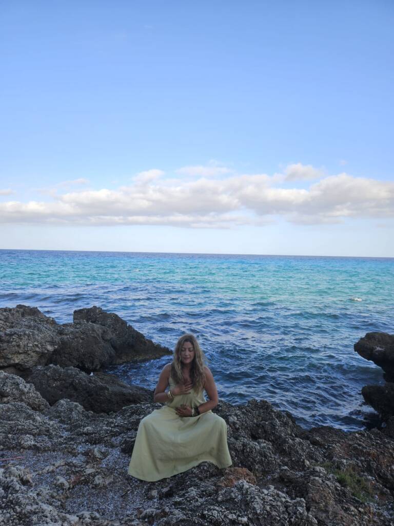 Dina Al Hidiq Zebib meditating by the sea on the rocks in mallorca 1