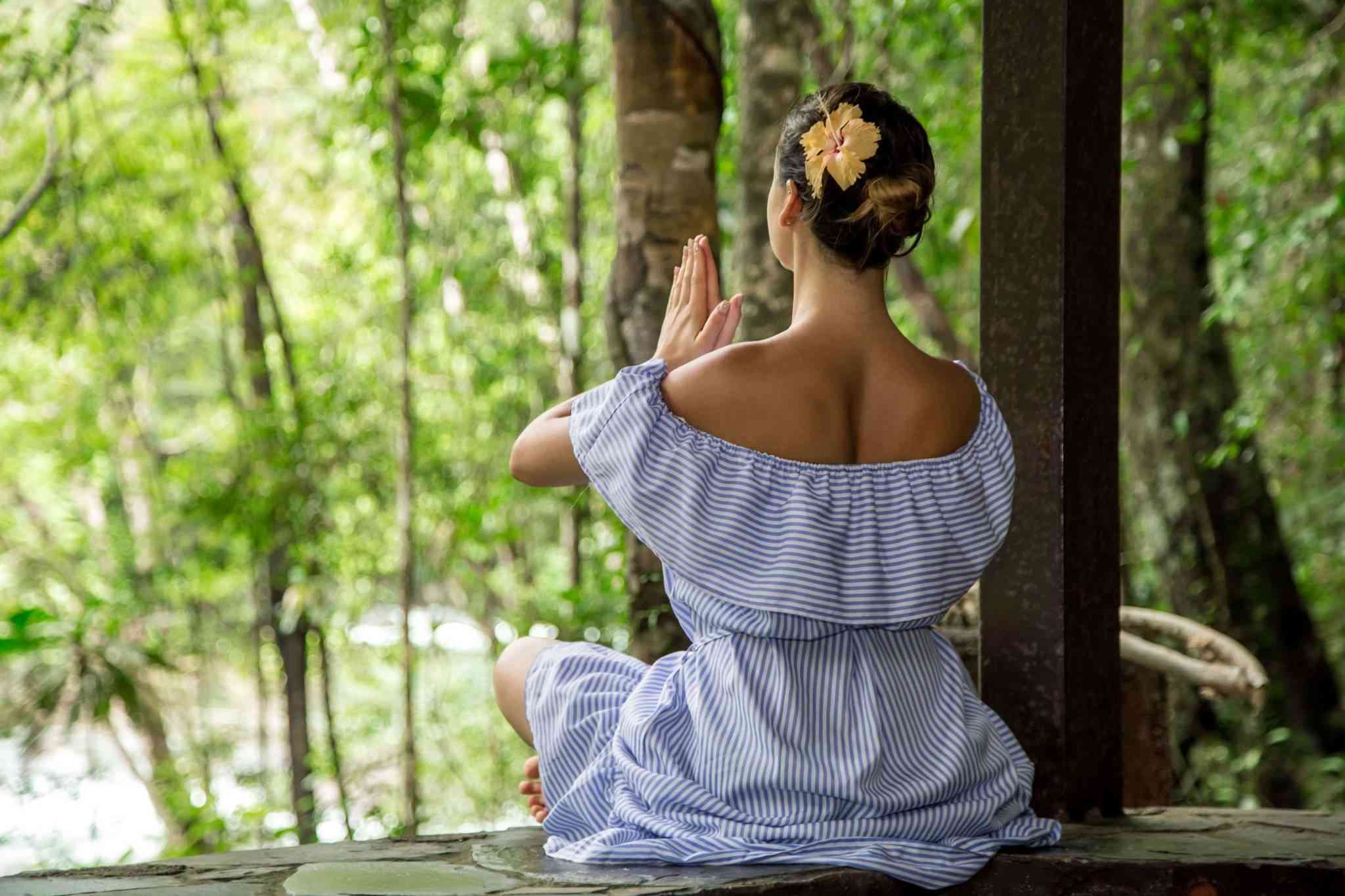 back view of woman meditating in forest