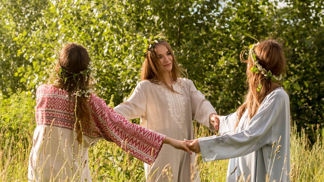 girls in a circle with flower crowns out in field dancing