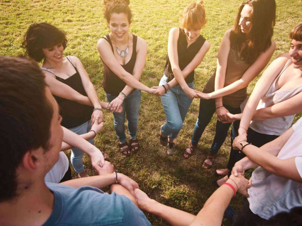 young happy people holding hands in circle