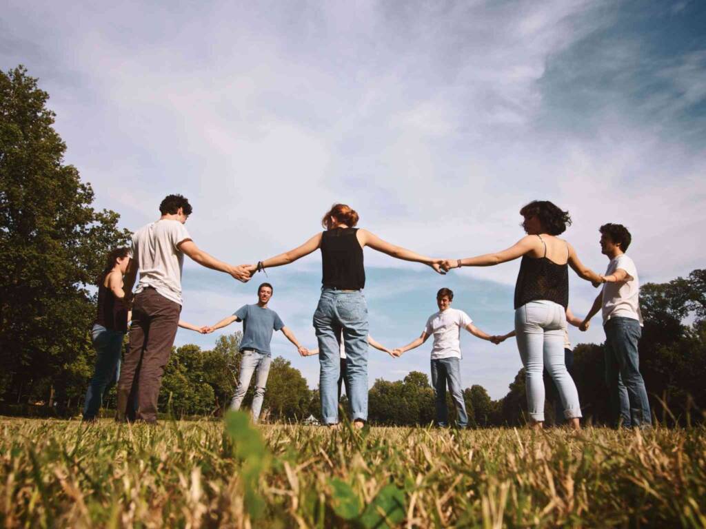 young people holding hands circle outdoors