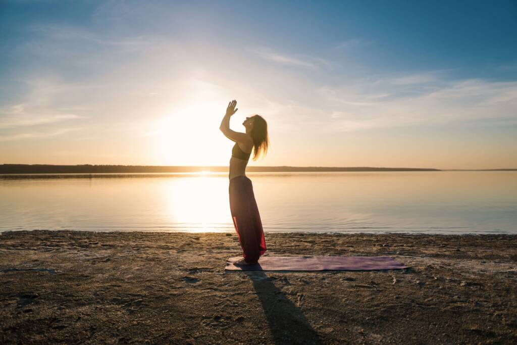 silhouette yoga woman on the beach at sunset